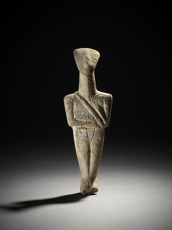 Marble figurine of a man of the 'hunter-warrior' type. Carved with diagonal shoulder strap and belt. Right arm folded across waist and left across chest. Ghosts of painted eyes on face. Slight damage to feet but otherwise complete, with repair at waist where two pieces joined. Surface heavily encrusted.