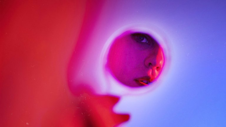 Woman looking at reflection in handheld mirror