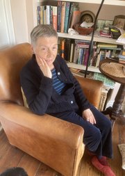 Alison Light sat in an armchair with a bookshelf behind her