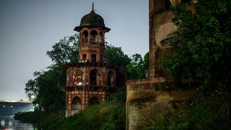 Nighttime view of the historic Chhatri on the banks of the Yamuna River, illuminated by gentle lighting.