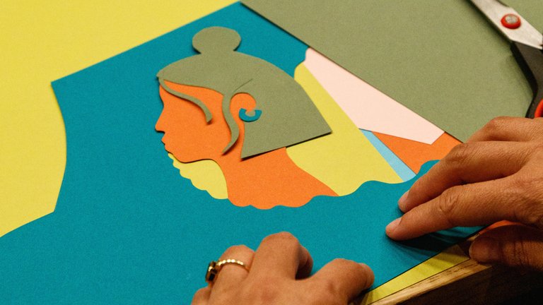 A close-up of paper cut art featuring a woman with hands in the shot