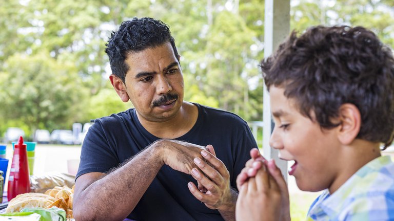 Australian Aboriginal man and boy talking together