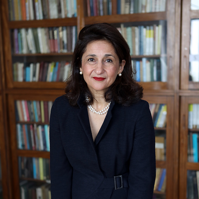 Photograph of Minouche Shafik with a bookcase in the background