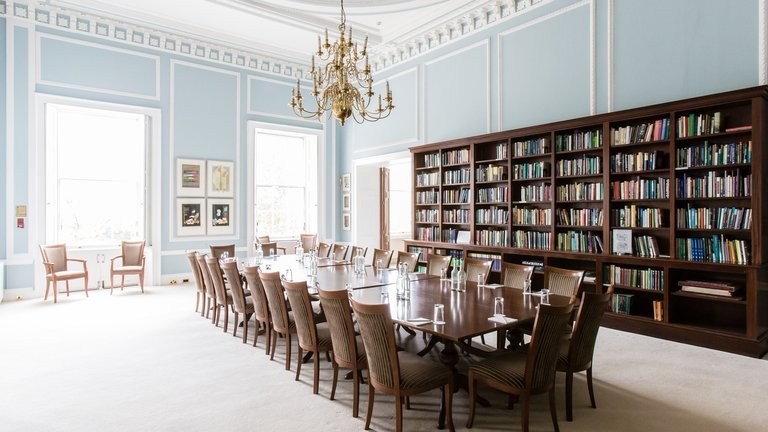 The Reading Room at the British Academy with a long table in the middle, high ceilings and a long bookshelf