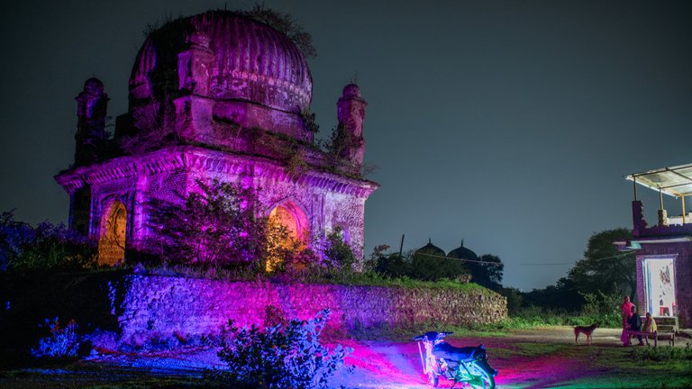 Night view of an illuminated ancient monument with colourful lights.