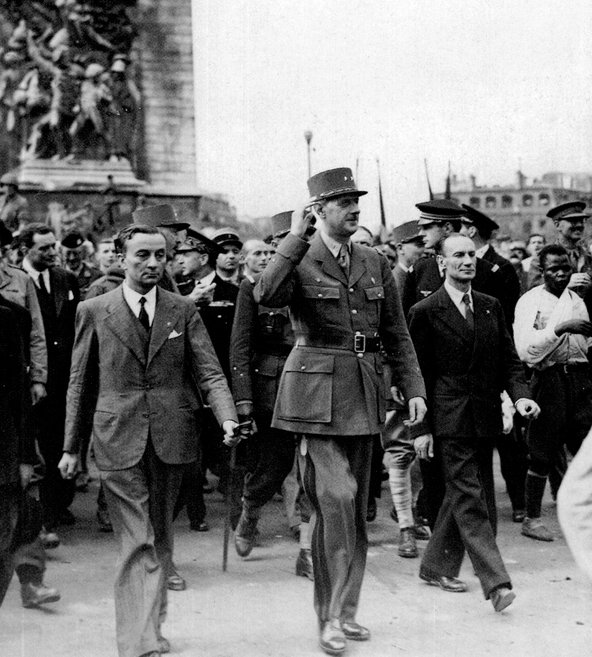 Georges Dukson can be seen on the rightmost edge of the photograph, walking at the front of the procession down Champs Elysees. De Gaulle, in the centre of the photograph, raises his arm to salute the onlookers.