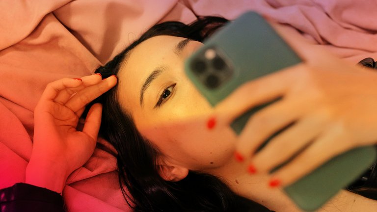 Close-up of girl lying down, looking at her phone and playing with her hair
