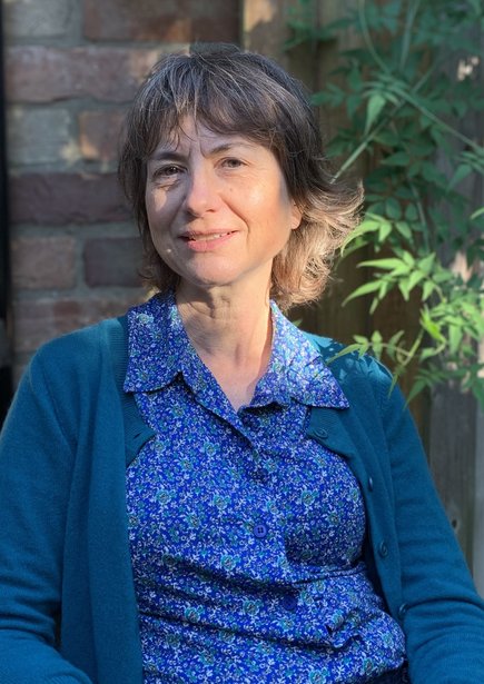 Portrait of a smiling Emily Gowers sat in some sunlight