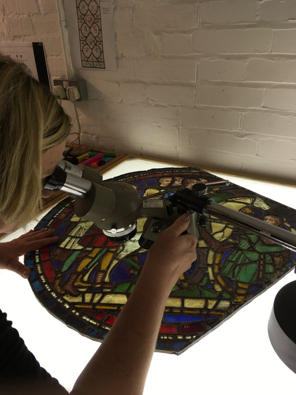 Examination of Pilgrims on the Road panel under microscope in Canterbury Cathedral stained glass conservation studio 2018.jpg