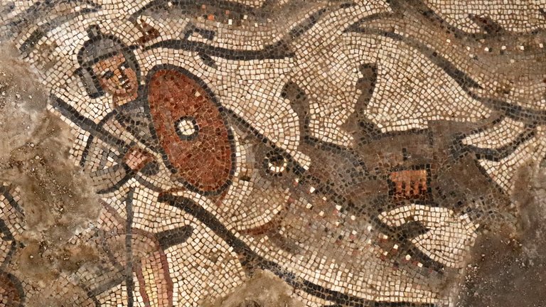 Photograph of ancient mosaic depicting a large fish swallowing a soldier.