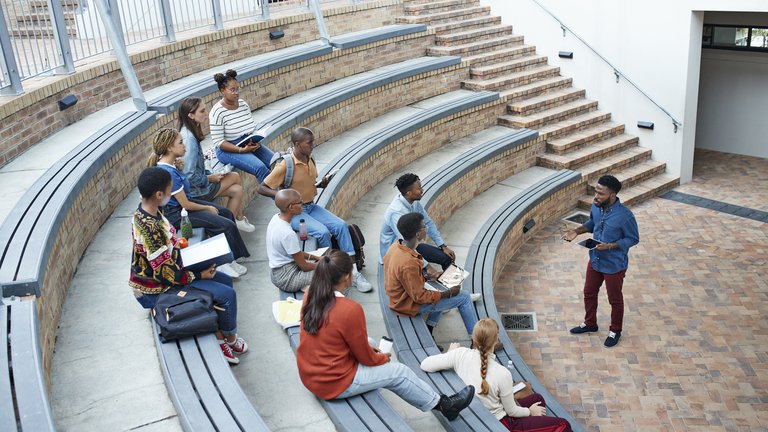 Male professor teaching young students at college