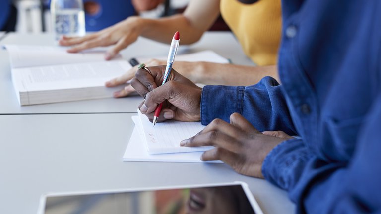 Person writing in a blank notepad.