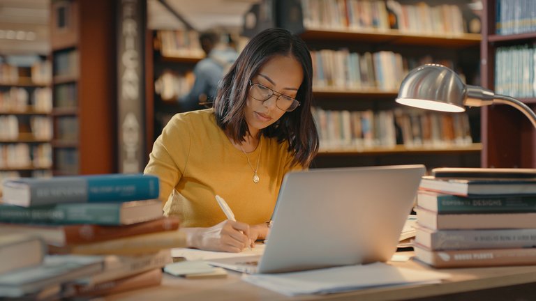 Young lady using a laptop to do research on the internet. Woman working on a project. Mixed race woman sending emails.