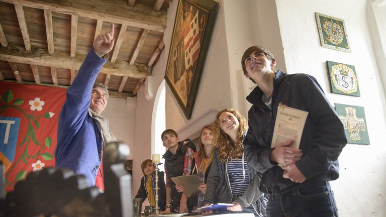 A man guides young people through an historic building.