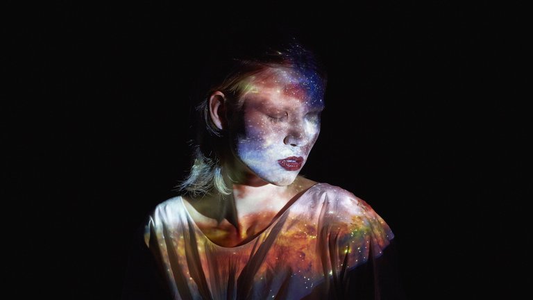 Image of woman lit by multi-coloured ethereal lights