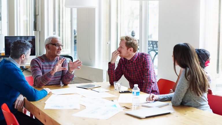 A group of colleagues have a discussion around a desk