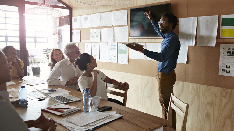 Person giving a presentation in a room to a small group of people.