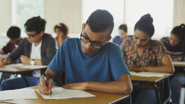 Students concentrate on exam papers