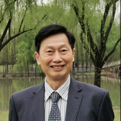 A photo of Zhenzhao Nie FBA outdoors in a suit against a backdrop of trees and a lake