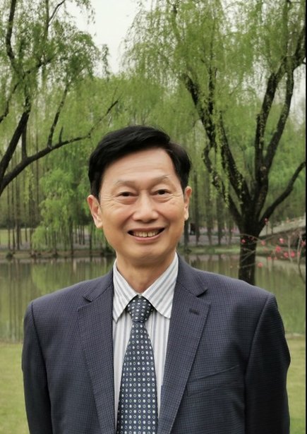 A photo of Zhenzhao Nie FBA outdoors in a suit against a backdrop of trees and a lake