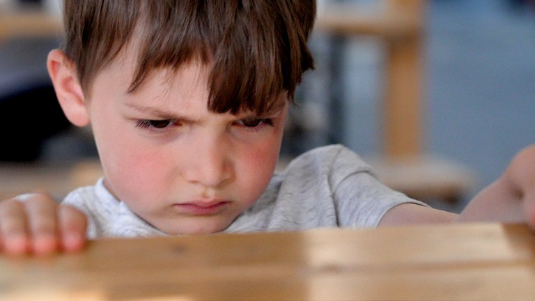 Angry looking child stares at table