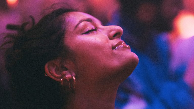 Close-up of woman with eyes closed dancing under coloured lights