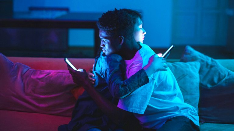 Two people looking at their phones while embracing