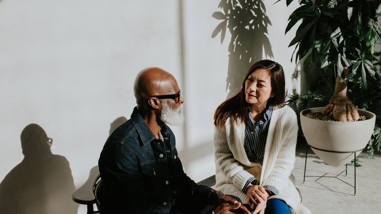 A woman makes eye contact with a man, looking at him kindly. He looks back at her.