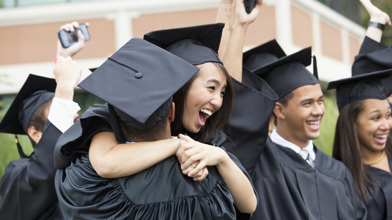 Graduates hugging outdoors.