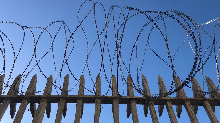 Low angle view of barbed wide fence set against the sky