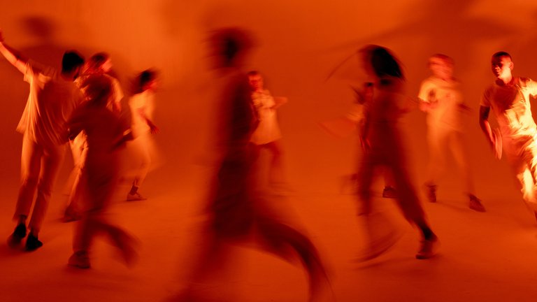 A group of people dancing in a circle with red lighting