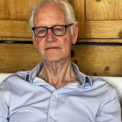 A photo of William Fitzgerald FBA in front of a panelled background.