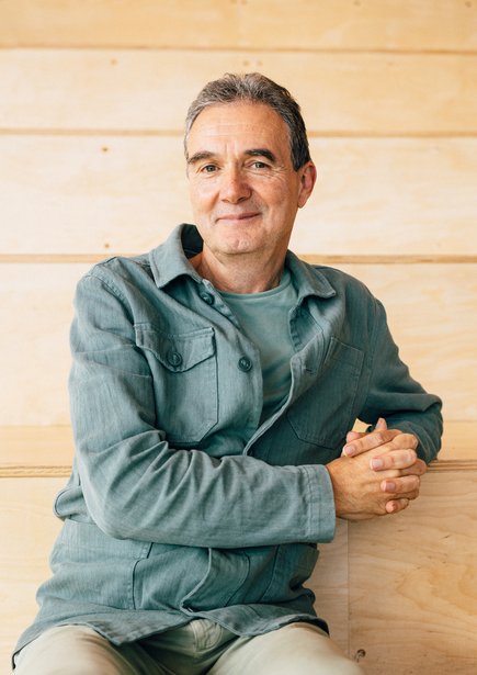 A portrait photo of Justin Lewis FBA in front of a panelled background.