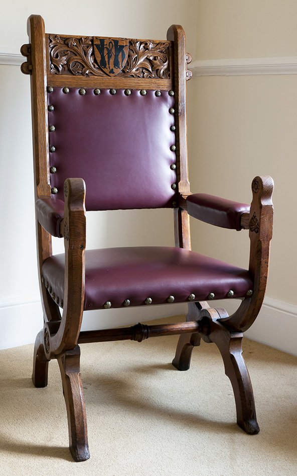 An ornate wooden President&#x27;s chair with purple cushioning