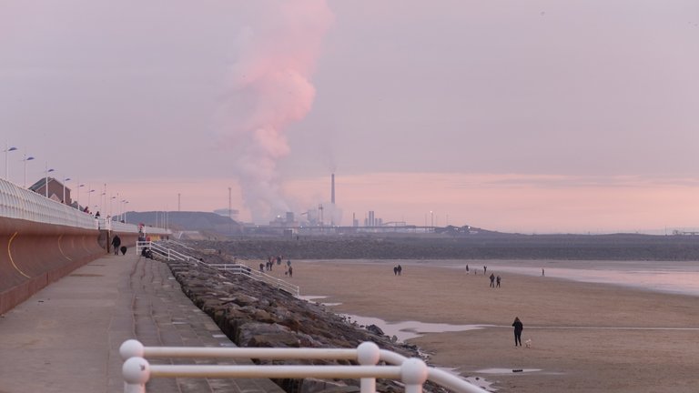 Image of the beach at sunset with a power station in the distant background