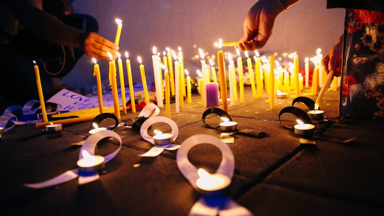 People lighting candles during candlelight vigil at night.