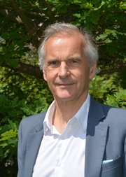 Headshot of Roger Matthews standing in front of trees and greenery