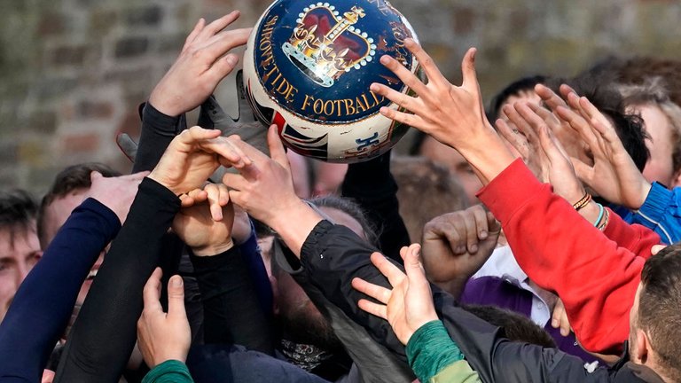 A close up of a set of hands battling for an airborne ball during the annual Ashbourne Royal Shrovetide 'no rules' football match