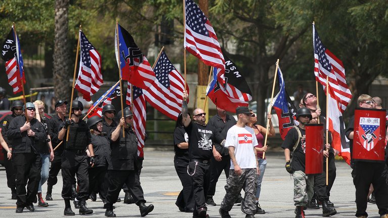 Members of the National Socialist Movement (NSM) march to their rally with flags