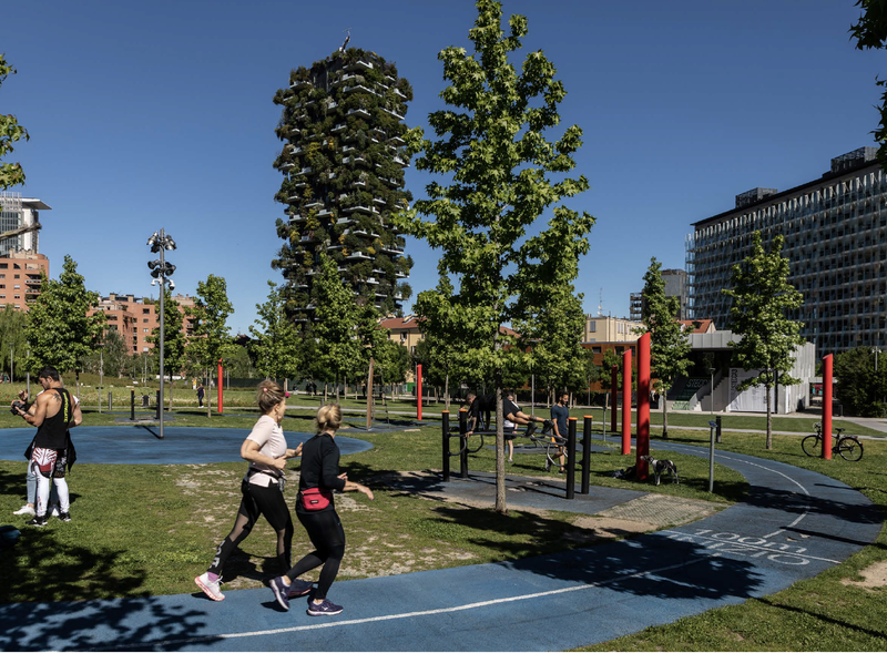 People exercising in an outdoor gym in a park near a block of flats