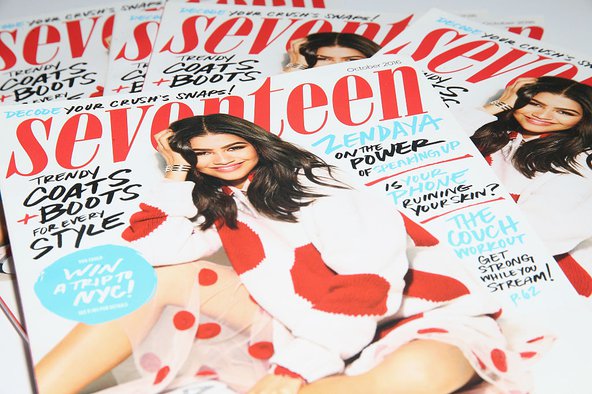 A photograph of several issues of Seventeen magazine spread out onto a surface with the magazine's name written in bright red at the top, echoed in the red polka dots on the covergirl Zendaya's sweater and skirt, who is smiling and sitting casually with one knee up for the image. The cover features various text about the issue's contents.