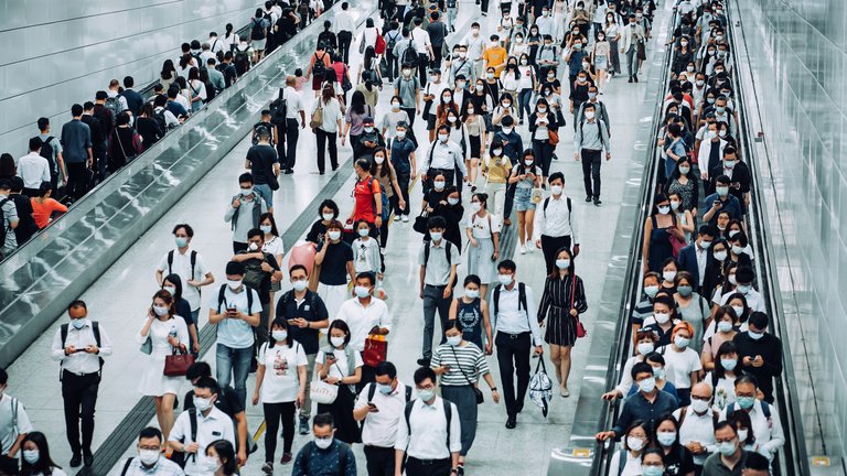 Commuters walk through a busy terminal wearing Covid masks