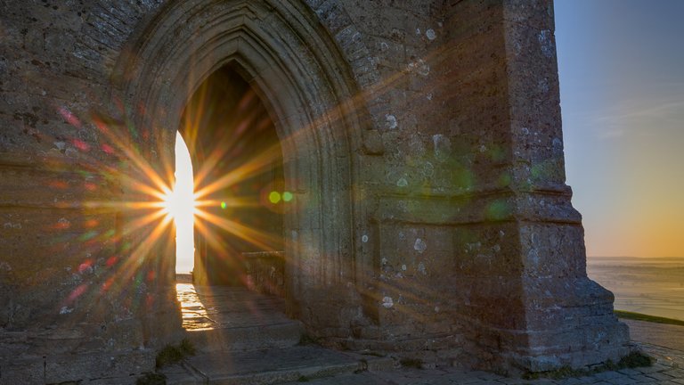 Rays of sunshine peaking through the gate opening of St Michael's Church tower situated on the top of the Glastonbury Tor hill.
