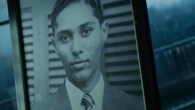 A still from the Stuart Hall Project film showing a young man wearing a suit and tie looking directly at the camera.