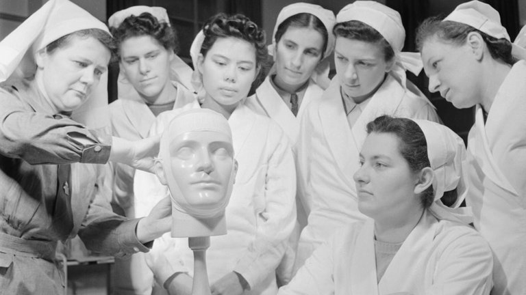 Group of nurses huddled around a mannequin