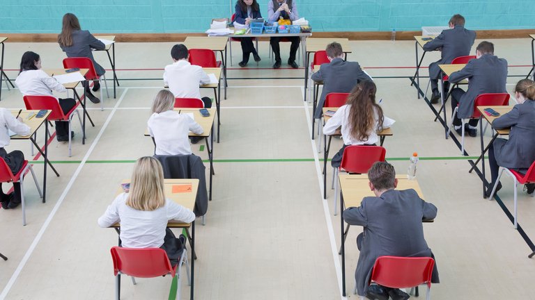 Teenage students sitting an exam in a gym