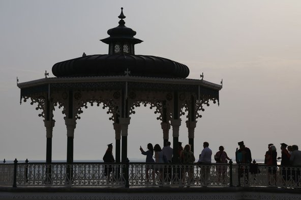 Silhouetted Sussex University students celebrate their graduation at the Bandstand on Brighton Beach, July 2019. Photo by Stephen Bardens / Getty Images