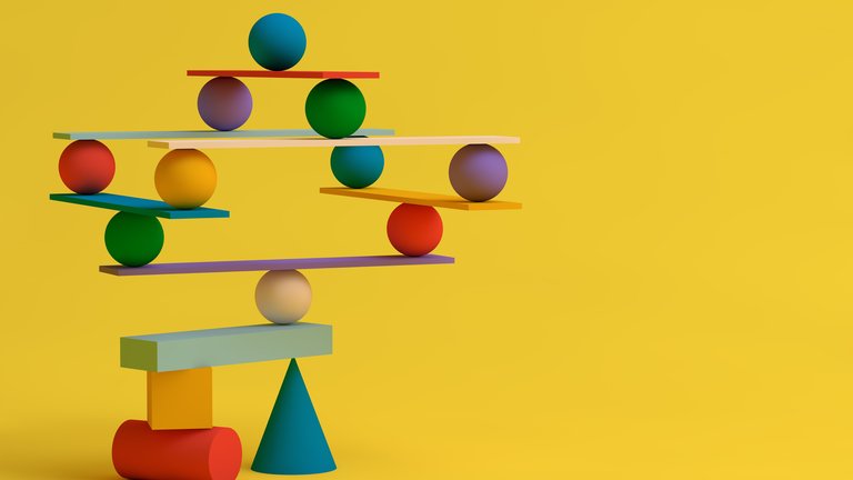 Coloured objects of different shapes and sizes balancing on small wooden slates on yellow background