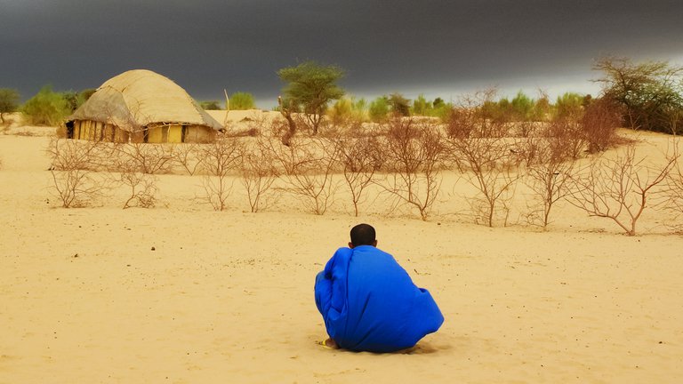 Tuareg man in the desert near Timbuktu in Mali, West Africa, looking at dark clouds waiting for the rain.