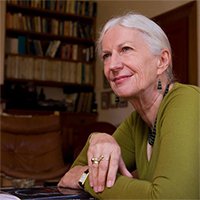 Professor Dame Anne Salmond FBA, smiling and looking up with bookshelves in the background.